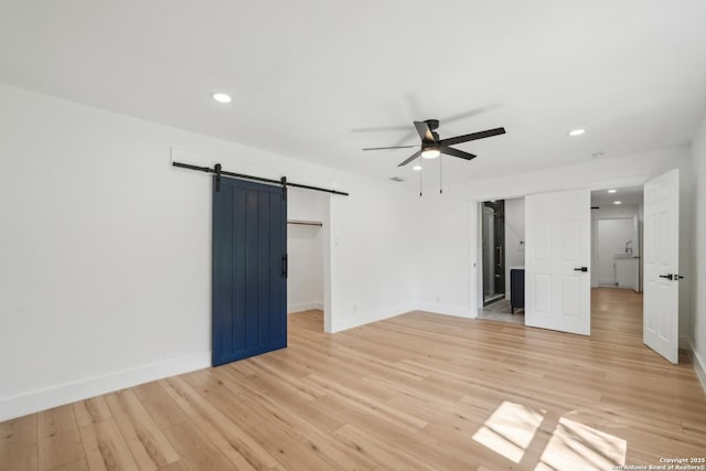 unfurnished bedroom with a barn door, recessed lighting, baseboards, and light wood-type flooring