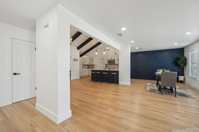 unfurnished living room with recessed lighting, beamed ceiling, baseboards, and light wood-style flooring