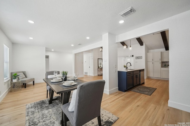 dining area with visible vents, light wood-style flooring, lofted ceiling with beams, recessed lighting, and baseboards