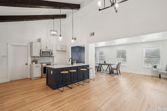 kitchen with a breakfast bar area, visible vents, light wood finished floors, light countertops, and appliances with stainless steel finishes