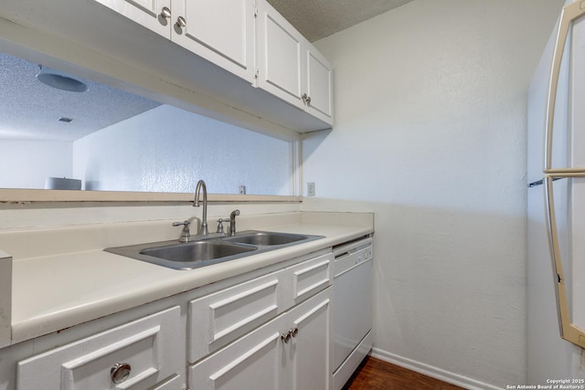 kitchen featuring white appliances, a sink, light countertops, a textured ceiling, and white cabinetry