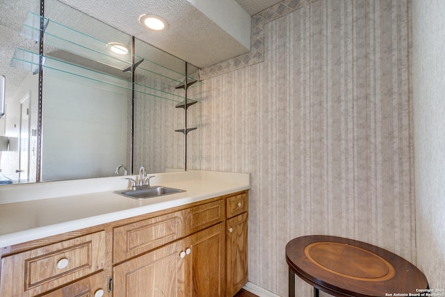 full bathroom with vanity, a shower, and a textured ceiling