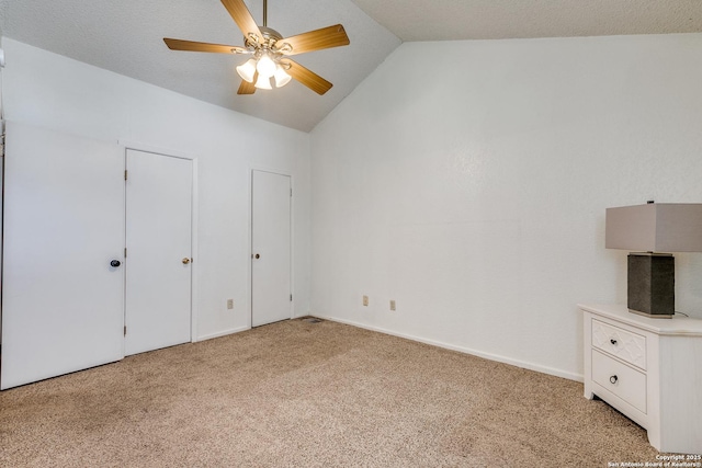 unfurnished bedroom with two closets, a ceiling fan, baseboards, light colored carpet, and vaulted ceiling