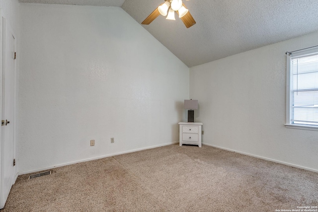 empty room with visible vents, carpet, ceiling fan, vaulted ceiling, and a textured ceiling