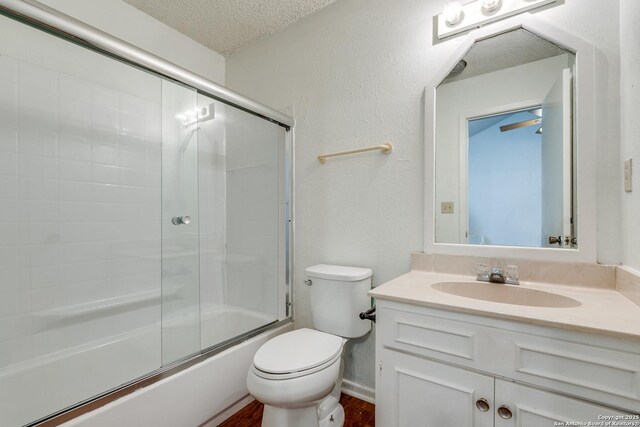 full bath featuring toilet, a textured ceiling, wood finished floors, enclosed tub / shower combo, and vanity