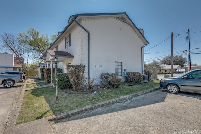 view of property exterior with a yard, fence, and central AC