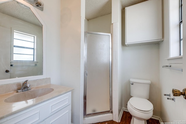 bathroom with a stall shower, toilet, vanity, and a textured ceiling