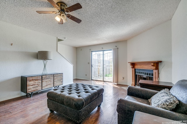 living room featuring a ceiling fan, wood finished floors, baseboards, and a fireplace