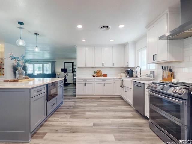 kitchen featuring a wealth of natural light, wall chimney range hood, visible vents, and appliances with stainless steel finishes