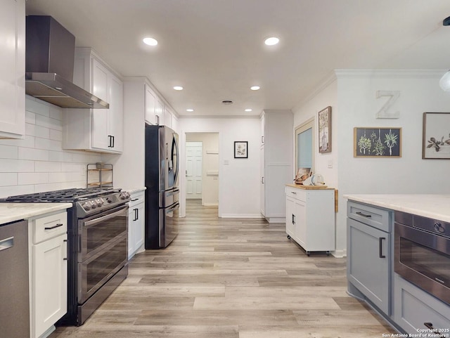 kitchen with light wood finished floors, ornamental molding, decorative backsplash, stainless steel appliances, and wall chimney exhaust hood