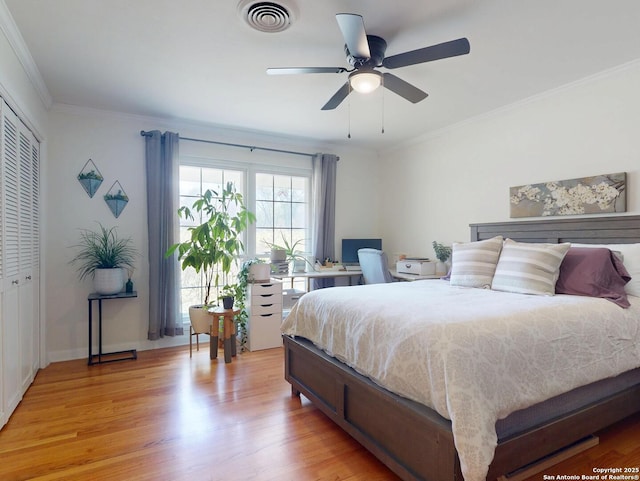 bedroom with a closet, visible vents, crown molding, and light wood-type flooring