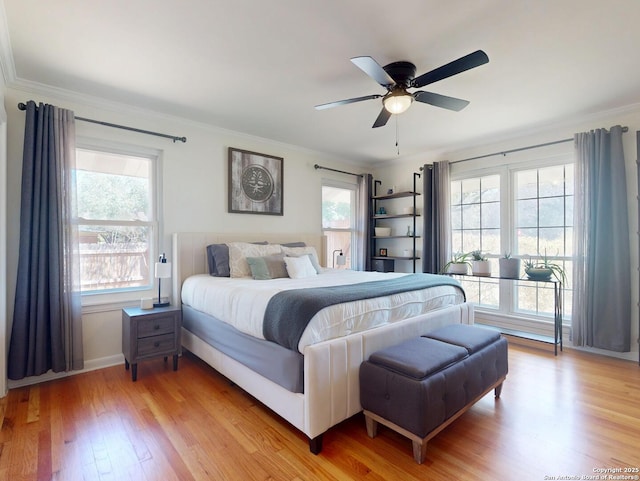 bedroom featuring crown molding, multiple windows, and light wood-type flooring