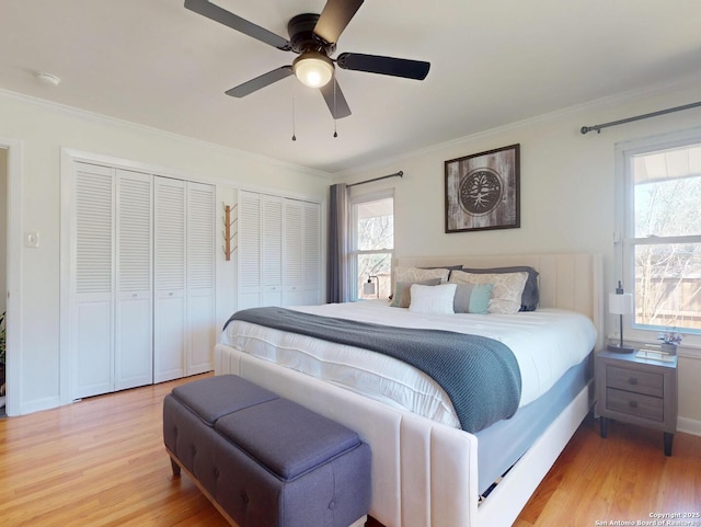 bedroom featuring multiple windows, two closets, light wood-type flooring, and ornamental molding