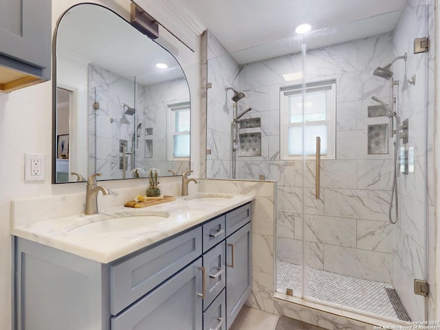 full bath with a sink, a marble finish shower, and a healthy amount of sunlight