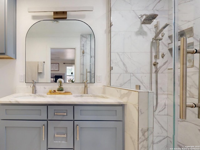 bathroom with a sink, a marble finish shower, and double vanity