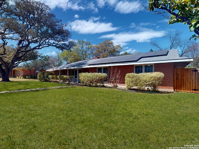 view of side of home with a lawn, solar panels, and brick siding