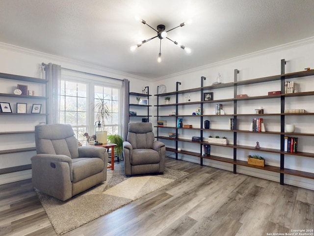 sitting room with a chandelier, wood finished floors, and ornamental molding