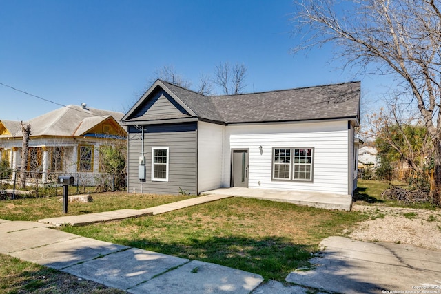 view of front of property with a patio, a front lawn, and a shingled roof