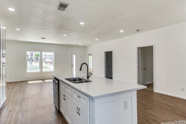 kitchen with visible vents, stainless steel dishwasher, wood finished floors, and a sink