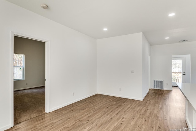 empty room with recessed lighting, wood finished floors, visible vents, and baseboards