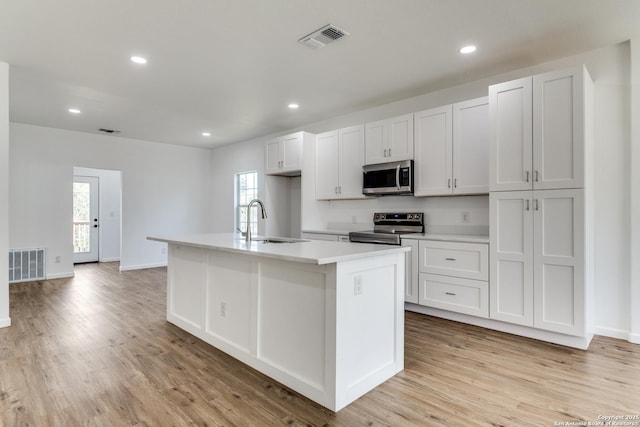 kitchen with a sink, visible vents, light wood-style floors, and appliances with stainless steel finishes