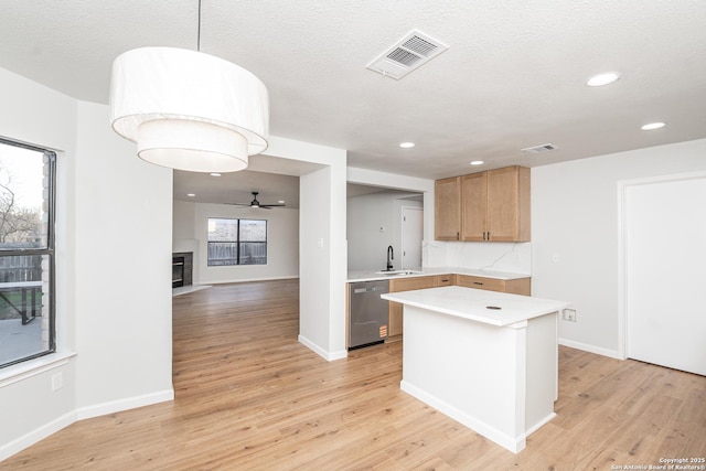 kitchen with visible vents, stainless steel dishwasher, light wood-style floors, light countertops, and ceiling fan