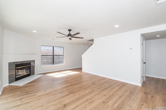 unfurnished living room featuring baseboards, ceiling fan, recessed lighting, light wood-style flooring, and a glass covered fireplace