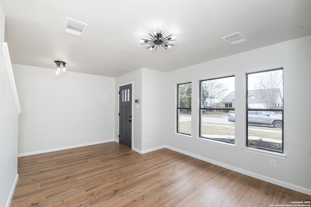 unfurnished room with visible vents, baseboards, and wood finished floors