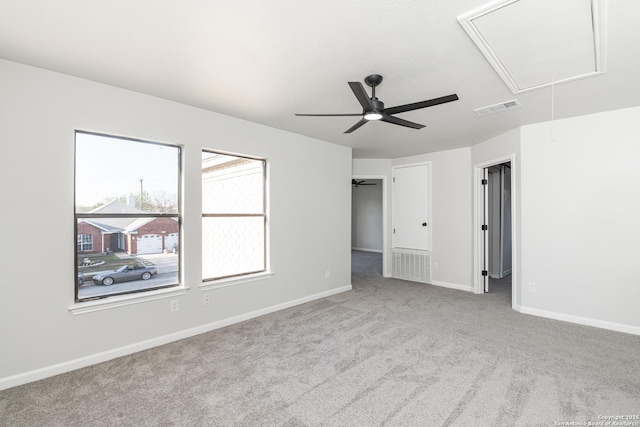 unfurnished bedroom with visible vents, a walk in closet, carpet floors, baseboards, and attic access