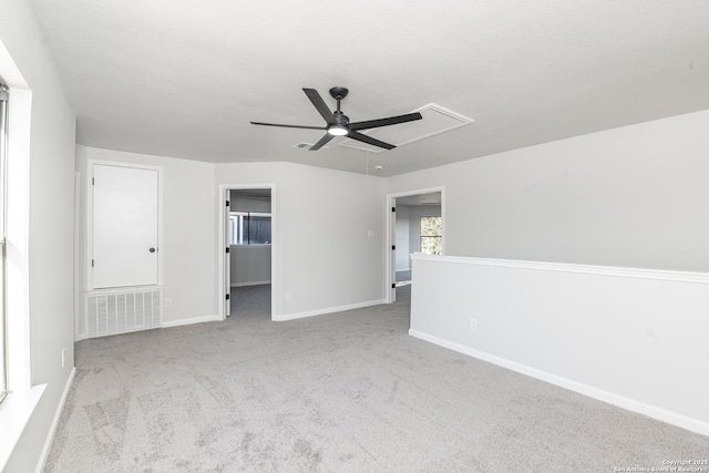 carpeted spare room with visible vents, baseboards, ceiling fan, attic access, and a textured ceiling