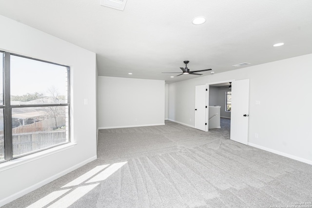 carpeted empty room featuring visible vents, a healthy amount of sunlight, and a ceiling fan