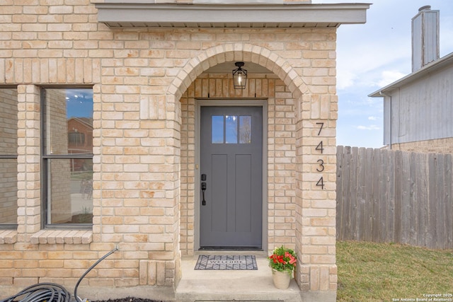 doorway to property featuring fence and stone siding