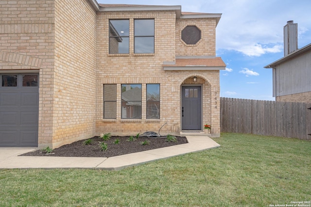 traditional-style house with a front yard, fence, and brick siding