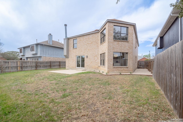 rear view of house featuring brick siding, a fenced backyard, a yard, and a patio