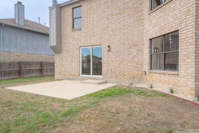 back of property with fence, a yard, a chimney, a patio area, and brick siding