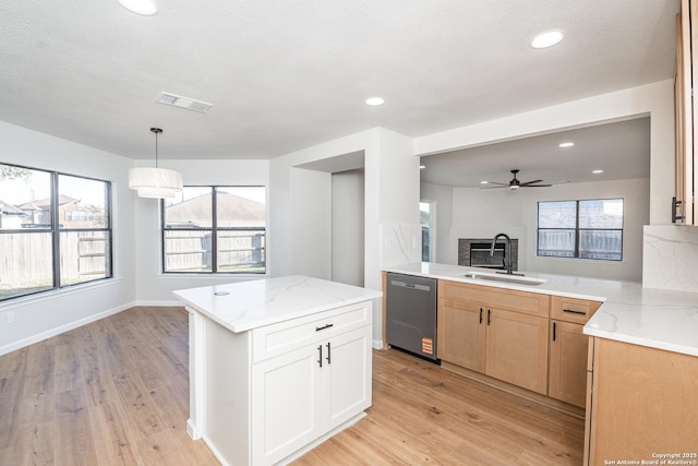 kitchen featuring a sink, light stone countertops, stainless steel dishwasher, and a ceiling fan