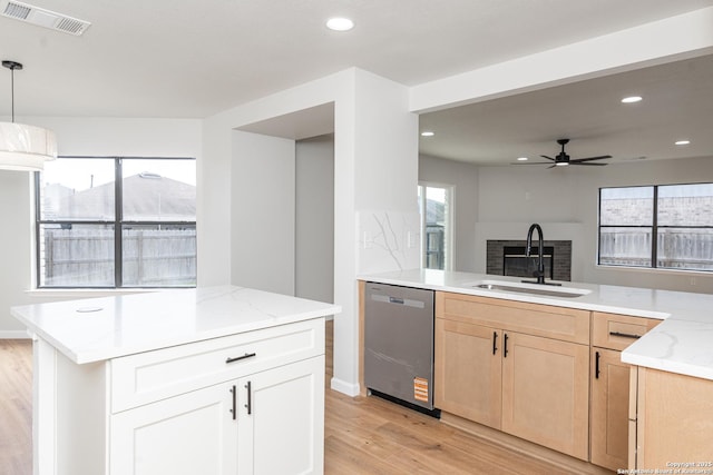 kitchen featuring visible vents, light brown cabinets, a sink, light stone countertops, and dishwasher