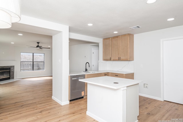 kitchen with a sink, visible vents, light wood-type flooring, and dishwasher