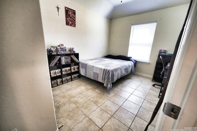 bedroom with light tile patterned floors and vaulted ceiling