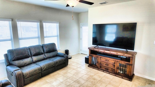 living area featuring tile patterned floors, visible vents, baseboards, and a ceiling fan