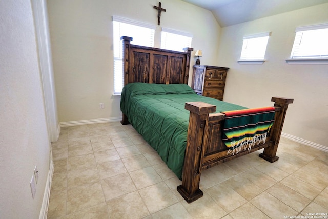 bedroom featuring vaulted ceiling, light tile patterned flooring, and baseboards