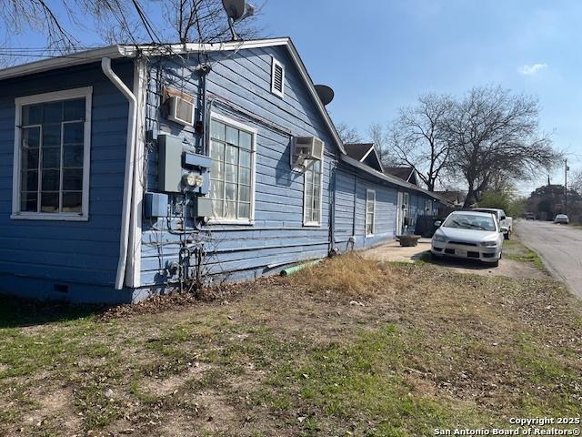 view of side of home with a wall mounted air conditioner and crawl space