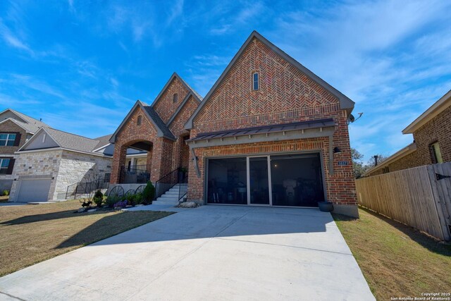 view of front facade featuring a front lawn, brick siding, driveway, and fence