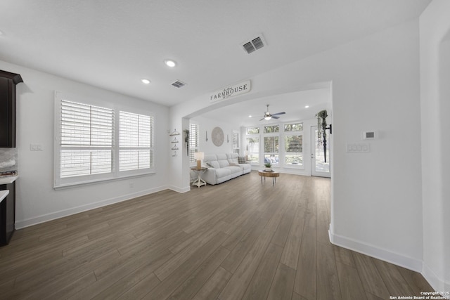 unfurnished living room with visible vents, baseboards, ceiling fan, and dark wood-style flooring