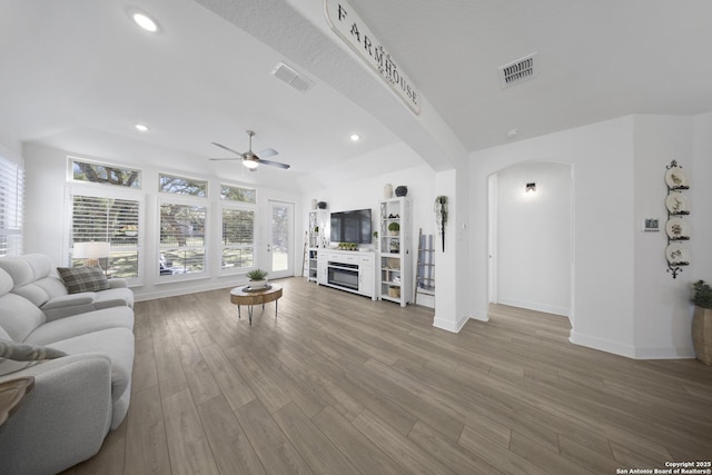 living area featuring a ceiling fan, wood finished floors, arched walkways, and visible vents