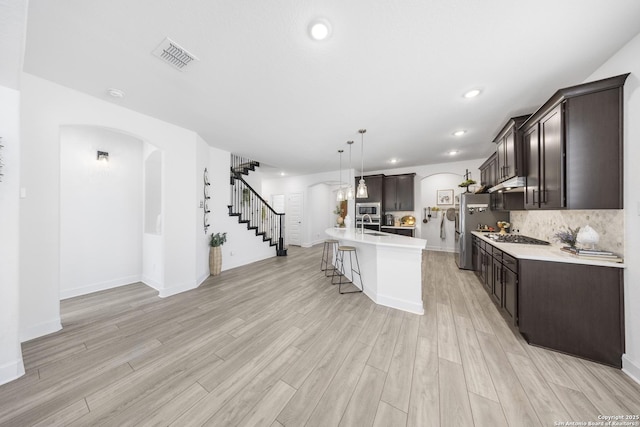 kitchen with dark brown cabinets, visible vents, and arched walkways