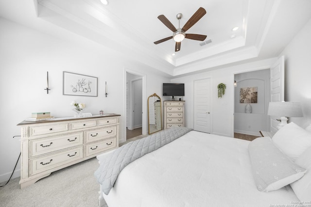 bedroom with a tray ceiling, baseboards, visible vents, and crown molding