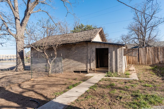 view of outdoor structure featuring entry steps, an outbuilding, and fence