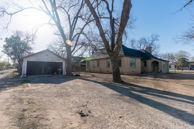 view of side of home with an outdoor structure, a detached garage, and a chimney