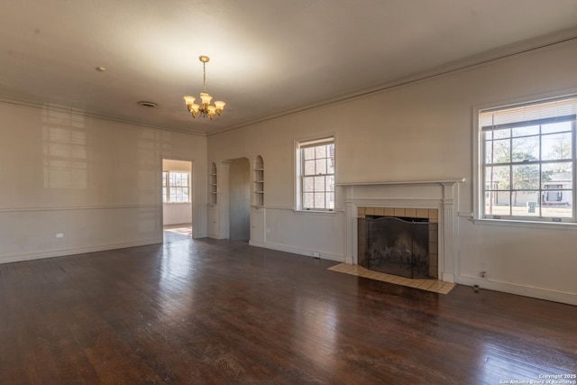 unfurnished living room with wood finished floors, a fireplace, arched walkways, crown molding, and a notable chandelier